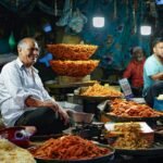 Lively street market in Srinagar, India showcasing local vendors selling traditional snacks under bright lights.
