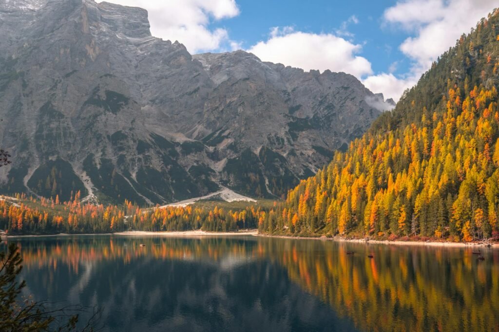 Stunning autumn landscape of Trentino mountains reflected in a serene lake, showcasing vivid fall colors.
