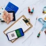 Flat lay of travel essentials including vaccination passport, euros, and medical supplies.
