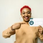 Cheerful woman pointing at an envelope with a cashback offer, emphasizing financial benefits.