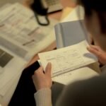 Adult woman reading a questionnaire and job postings indoors at a table, focused and contemplative.