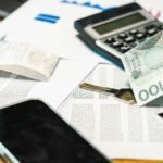 Close-up of financial documents, calculator, and Polish Zloty currency on a desk.