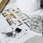 Floor plan with cash, keys, and hard hat symbolizing real estate investment and property planning.