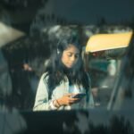 Young woman using smartphone in a vibrant street scene in New Delhi, India.