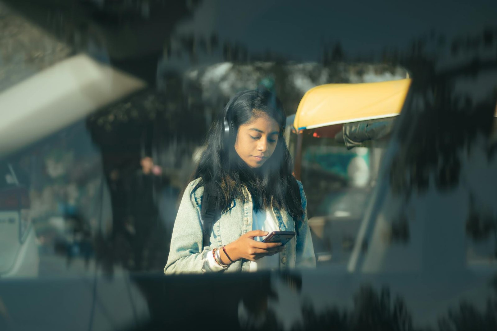 Young woman using smartphone in a vibrant street scene in New Delhi, India.
